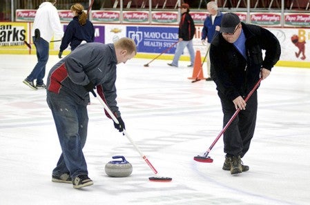 Sam Thorpe, left, and Troy Goodwater sweep during a curling match in Riverside Arena Monday. Rocky Hulne/sports@austindailyherald.com