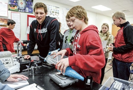 Caleb Philstrom puts the egg container for he and Logan Braaten’s (left) egg on a scale to weigh it with the egg before it was taken to the top of the school.