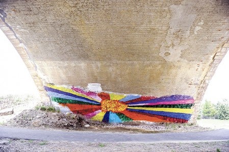 A colorful picture of sun and its rays spreads out across the base of Roosevelt Bridge. The mural was painted in an attempt to cover up graffiti, but has drawn the ire of the County Commissioners instead who claim it looks bad. Eric Johnson/photodesk@austindailyherald.com