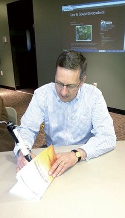 Senior Pastor at Our Savior’s Lutheran Church Glenn Monson signs one of his books about Law and Gospel preaching for someone Wednesday night at his book-signing event. Photo provided