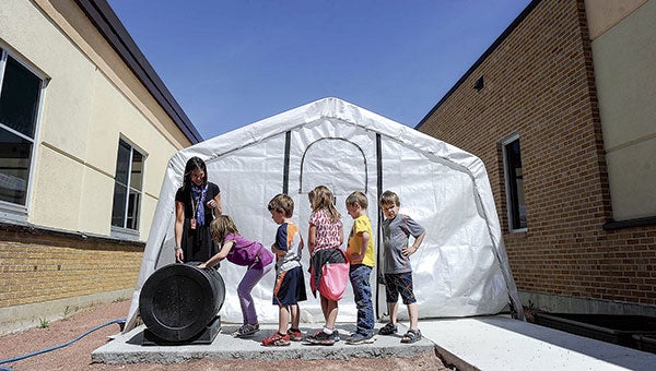 Woodson Kindergarten Center students take turns rolling a compost bin in front of the center’s greenhouse Thursday.  Photos by Eric Johnson/photodesk@austindailyherald.com