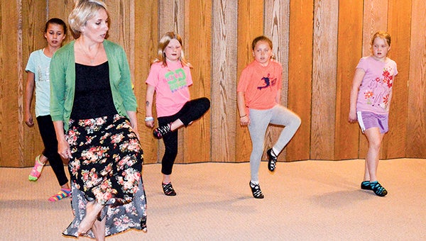 Dance instructor Sandra Ewing shows several students how to properly cut during an Irish dance lesson Thursday at Little Cedar Lutheran Church in Adams. -- Trey Mewes/trey.mewes@austindailyherald.com
