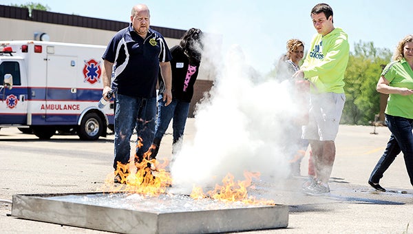 Trinity DeRooy puts fire retardant on a fire as firefighting program coordinator Brian Staska watches during Riverland Community College’s Healthcare Career and Exploration Day Thursday. -- Photos by Eric Johnson/photodesk@austindailyherald.com