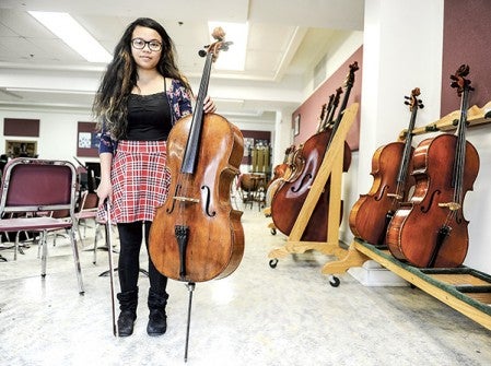 Austin High School junior Abby Sencio shows off a cello donated by former teacher Jean Miller a number of years ago. Current orchestra director Gene Schott had the cello refurbished and now the cello has been appraised at $38,000. Eric Johnson/photodesk@austindailyherald.com
