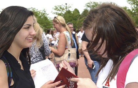Bailey Mueller (right) signs Gaby Marconi’s yearbook.