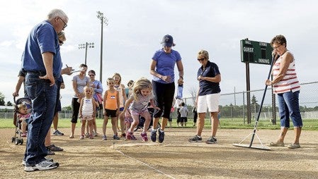 Jamye Lamers jumps with her daughter Mallory in the long jump. RIGHT: Camryn Deters competes in the softball throw.