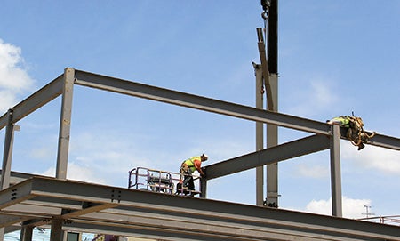 Workers secure beams for the framing of the new Spam Museum. 