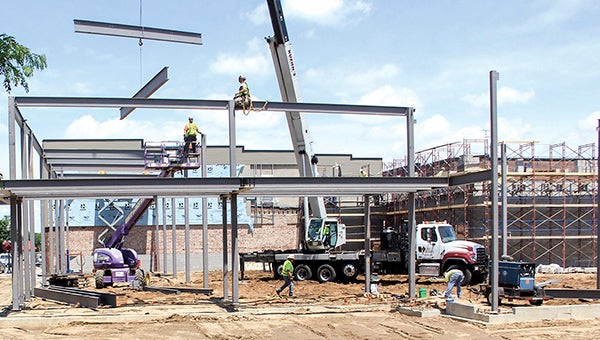 Workers secure beams for the framing of the new Spam Museum between Second and Fourth Avenues on the east side of North Main Street Wednesday. Construction started in April, and the structure of the building began taking shape this week. -- Photos by Jason Schoonover/jason.schoonover@austindailyherald.com