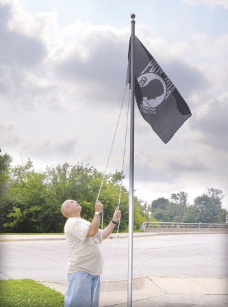 Legion Commander Kirk Olsen raises a flag at the start of the Field of Flags Tuesday morning at Bandshell Park.  