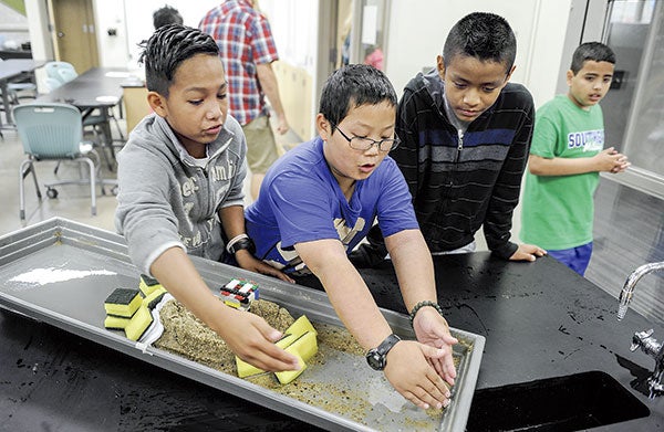 Andrew Hernandez, from left, Leon Kong and Yahir Amador, all from Albert Lea, go over ideas on how to make their experiment in flood control better during Project E3 Thursday at I.J. Holton Intermediate School. Eric Johnson/photodesk@austindailyherald.com