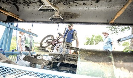 Matt Freechack loads a bicycle into a trailer that a group of volunteers drug out of Mill Pond Friday afternoon, part of the Jay C. Hormel Nature Center’s Water Festival.  Eric Johnson/photodesk@austindailyherald.com