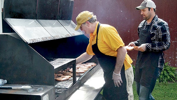 Mark Kanne (left), kitchen manager of Hy-Vee, and Brian Neuvirth from Mower County Pork Producers cook Windsor pork chops at the start of the Chamber of Commerce Ag Appreciation Cookout last year. -- Herald file photo