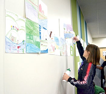 A student takes down a picture she drew.