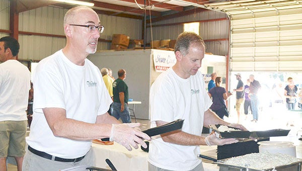 Paul Baessler, left, and Scott Felten serve up pork chops for the Ag Appreciation Day sponsored by the Austin Area Chamber of Commerce at the Mower County Fairgrounds. 