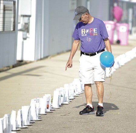 Wayne Rustad, a  four-year cancer survivor, walks down the line of luminaries during the Relay for Life Saturday night at the Mower County Fairgrounds.  Eric Johnson/photodesk@austindailyherald.com