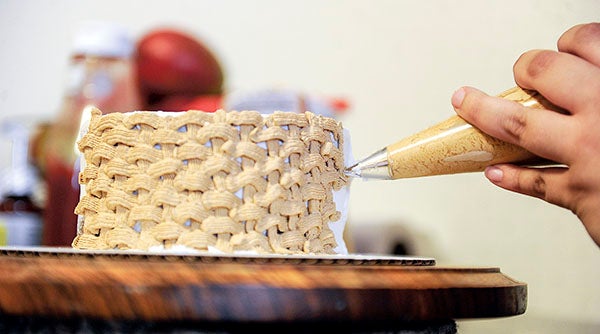 Amanda Schramm creates a weave pattern on one of her cakes. Eric Johnson/photodesk@austindailyherald.com