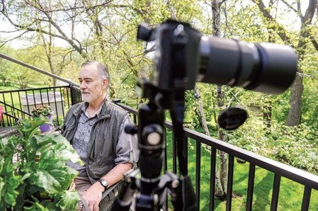 Tim Rietz sits on his patio while a camera points out towards the backyard. Tim spends a lot of time in the trees behind the house looking for any images he can. Photos by Eric Johnson/Austin Living