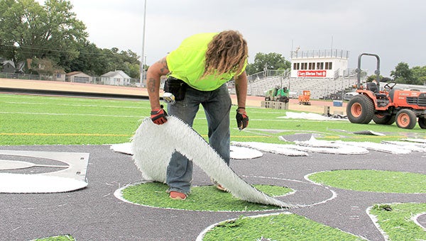 Doug Bywater cuts out numbers for the turf at Larry Gabrielson Track and Field.