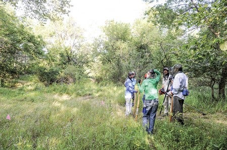 Volunteers talk about their next course of action while clearing out a trail for a new mountain biking course near Todd Park. Eric Johnson/photodesk@austindailyherald.com