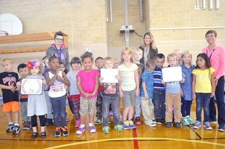 Students in Julie Loveland’s kindergarten class pose with some of the certificates Woodson Kindergarten Center received for being a Sustaining Example School after a ceremony Friday to recognize Woodson staff. Trey Mewes/trey.mewes@austindailyherald.com