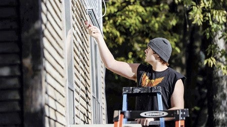 Hunter Pfeifer scrapes the sides of a house where volunteers worked to paint as part of the Community Home Improvement Project. Eric Johnson/photodesk@austindailyherald.com