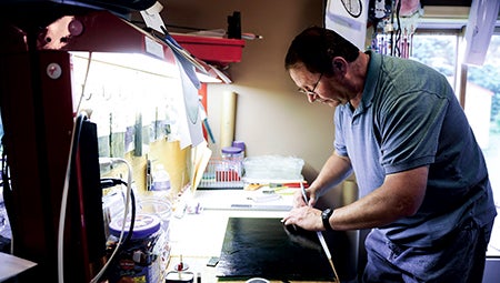 Jeff Peterson cuts a piece of glass at his work bench.