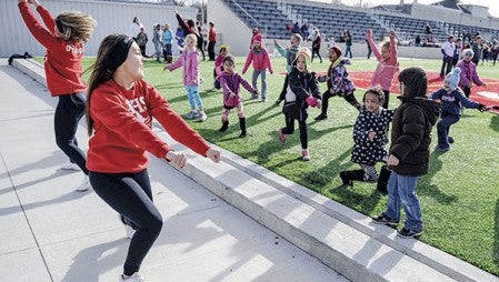 Austin football cheerleader Alyssa Abrego helps lead young girls through a cheer at Art Hass Stadium Saturday morning, part of a football camp that featured Minnesota Vikings cheerleaders.