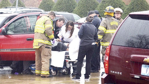 Firefighters and paramedics help a patient Monday morning on Third Avenue Northeast.  Fire chief Jim McCoy later confirmed a driver had a medical emergency and hit a parked vehicle. A large cloud of smoke was briefly seen, which McCoy said was from tire burnup after the driver’s foot remained on the gas after the car came to a stop.  Jenae Hackensmith/jenae.hackensmith@austindailyherald.com