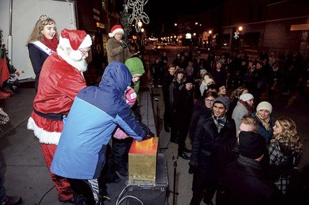 Santa Claus gets some help as he pushs the button to light the downtown decorations during Christmas in the City Friday night on Main Street. Eric Johnson/photodesk@austindailyherald.com