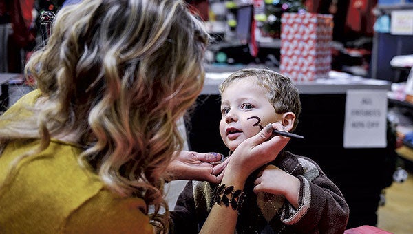 Three-year-old Louis Miller of Austin gets his face painted by Lizzy Wolterman at Games People Play Tuesday night during Christmas in the Northwest. Louis turned three on the same day. 