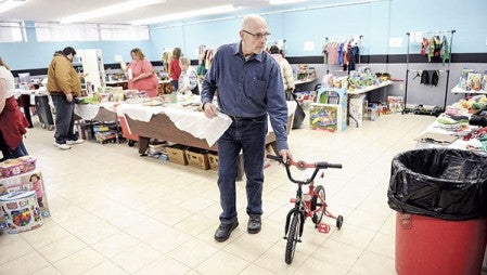 Volunteer Greg Olson wheels a bike to the door as people showed up Thursday for the Salvation Army’s annual toy distribution. Eric Johnson/photodesk@austindailyherald.com