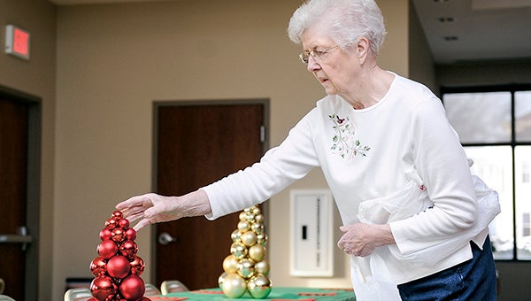 In 2013, Gladys Bliss puts out a table setting as her family gets the St. Olaf dining room ready for the annual community Christmas Day dinner Tuesday morning. The meal was started in 1998 in honor of Gladys’ son who died in a dirt bike accident in 1998. -- Herald File Photo