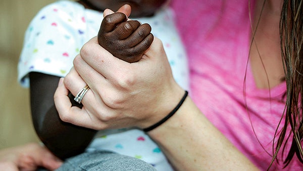 Allyson Klankowski holds the hand of a little girl the family is adopting. The child was a foster child, one of many the family has opened their doors to. Eric Johnson/photodesk@austindailyherald.com
