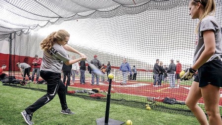 Adison Medgaarden, left, and Hannah Biwer take turns on a batting tee underneath the dome during an open house. 