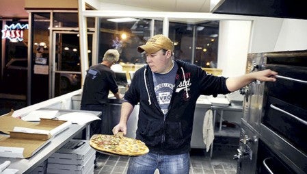 Jeremy Peck takes a pie from the oven Wednesday night at Georges Pizzas. A 22-year employee of George’s, Peck will take over much of the day to day routine of the restaurant after it was purchased by his parents Larrry and Deborah Peck.  Herald file photo