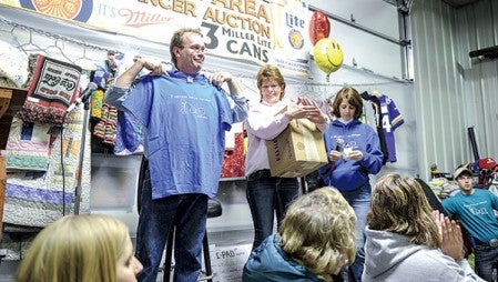 Lyle Area Cancer co-chair Larry Ricke displays a shirt given him by Teresa Slowinski, right, after it was announced the auction hit the $2 million mark last January. Herald file photo
