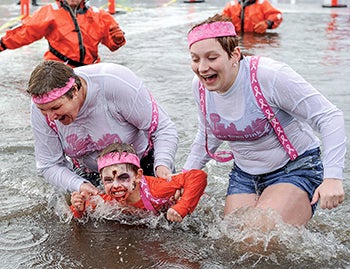 Six-year-old Lucas Klitzman is helped out of East Side Lake by family members Emily McAlister, right, and Barb McAlister after their jump in the Polar Plunge Saturday afternoon. Hope McAlister also took part in the jump. 