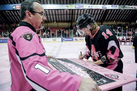 The Bruins’ Jan Stefka signs a picture that was to be auctioned during the jersey auction at Paint the Rink Pink Saturday night at Riverside Arena. 