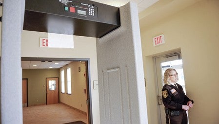 Mower County Sheriff Terese Amazi, standing next to a metal detector at the Jail and Justice Center Tuesday, talked about the need for more safety.  -- Eric Johnson/photodesk@austindailyherald.com