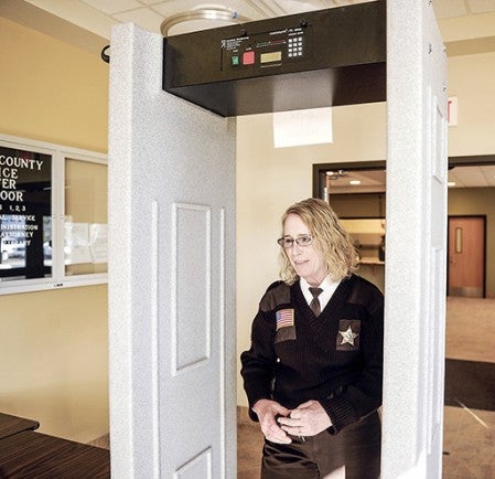 Mower County Sheriff Terese Amazi walks through the county’s lone metal detector at the Jail and Justice Center Tuesday. 