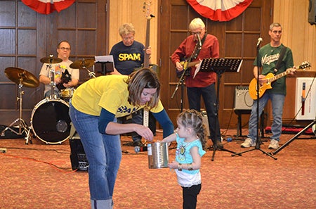Hormel Historic Home Director Holly Johnson holds a bucket while 2-year-old Chanel Valencia chooses a winner for prizes.