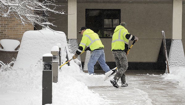 A pair of workers clear snow from the walk leading to Austin Utillities Thursday morning. Austin and the surrounding area received between 7 and 10 inches of snow Wednesday into Thursday. Eric Johnson/photodesk@austindailyherald.com