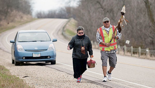 Sharon Day walks along Highway 68 near Courtland, Minn., Tuesday with Frankie Jackson. Day is carrying water from the headwaters of the Minnesota River to its meeting point with the Mississippi River. Jackson is carrying a staff that’s for protecting the water carrier. Jackson Forderer for MPR News