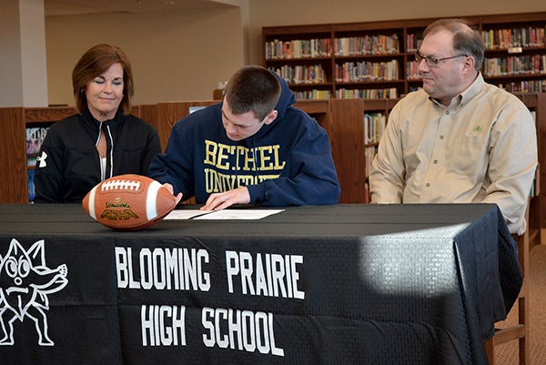 Blooming Prairie senior Anthony Nelson signs his letter of commitment to play college football at Bethel University next season. Looking on are Anthony's parents Lois and Brian. Rocky Hulne/sports@austindailyherald.com