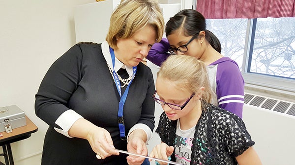 Mentor Jennifer Lawhead works with students Gissell Alejo Torres and Kailee Aldrich during the Science Fair Mentoring Project in the program’s second year at Neveln Elementary School. Photo provided.