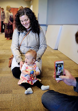 11-month-old Clara Hamer, with her mom, Kelli Hamer, plays with a rattle and bells as dad Noah Hamer takes video Saturday at the Austin Public Library, part of a demonstration by the MacPhail Center for Music in conjunction with Matchbox. 