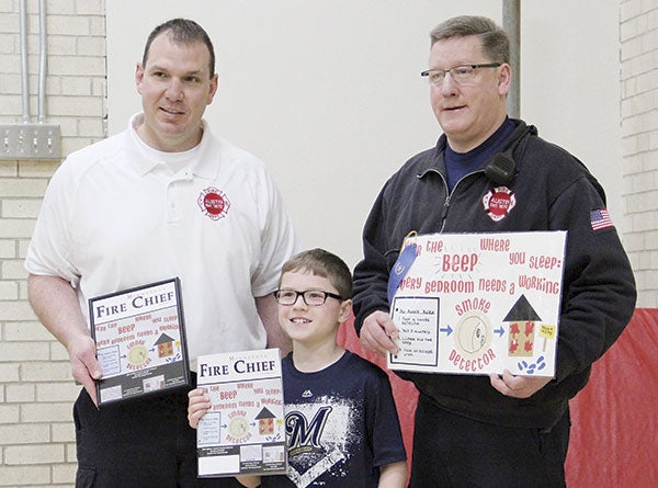Southgate Elementary School fourth-grader Brandon Kuhnke, 9, center, won the 2015 Minnesota State Fire Chiefs Association Poster Contest. He’s pictured with Austin Fire Chief Jim McCoy, left, and Fire Inspector Tim Hansen. Jason Schoonover/jason.schoonover@austindailyherald.com