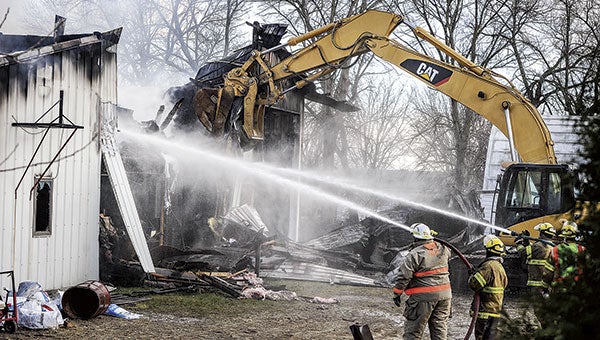 An excavator pulls away a portion of a wall as firefighters put water on a bodyshop in Grand Meadow Friday afternoon.  Eric Johnson/ photodesk @austindaily herald.com