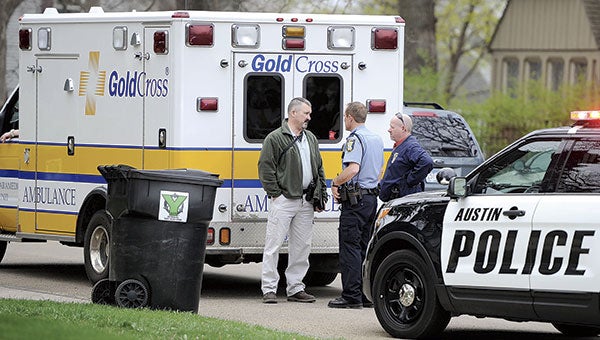 Detectives and an Austin Police officer talk outside of a Gold Cross ambulance after being called to the scene of a stabbing on Fourth Street Southwest Tuesday morning.  Eric Johnson/photodesk@austindailyherald.com