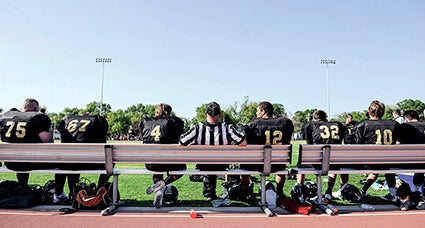 Players from the Southeast Minnesota Warhawks and a referee sit on the bench at halftime against the North Iowa Bucks Saturday.